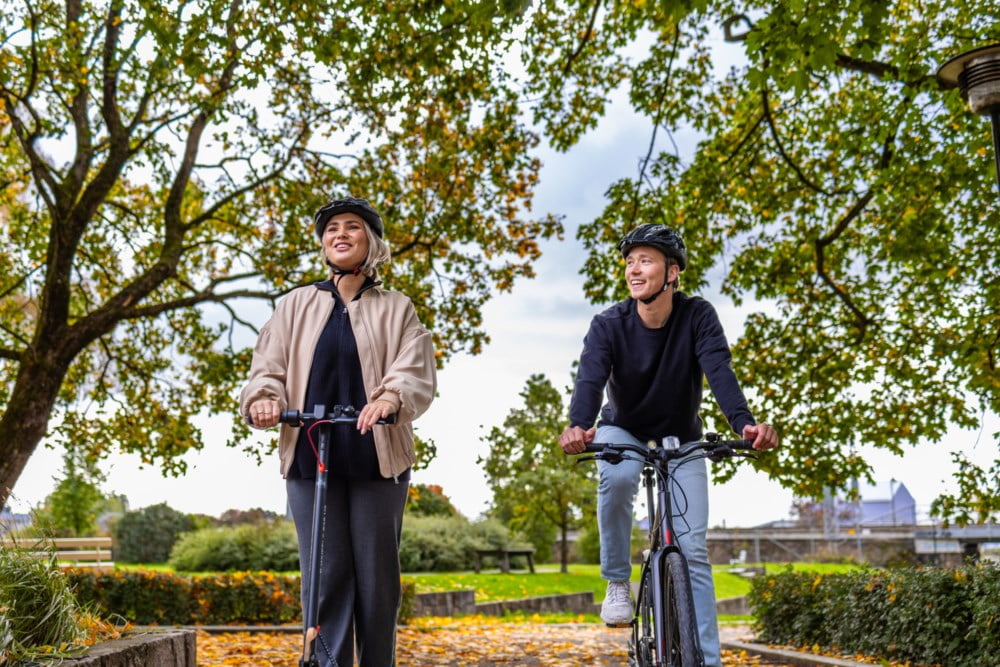 Ung jente på elsparkesykkel og ung gutt på sykkel